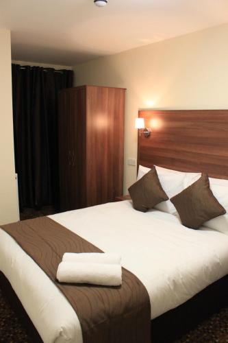 a bedroom with a large bed with a wooden headboard at Prince Regent Hotel Excel London in London