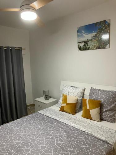 a bedroom with a bed with yellow and gray pillows at La Maison d 'Hippolyte in Vieux-Habitants
