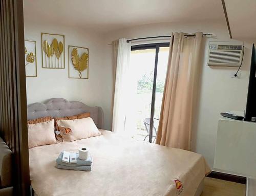 a bedroom with a large bed with a window at CozyLuxe Staycation at Pine Suites Tagaytay by Crown Asia in Tagaytay