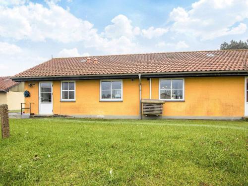 a yellow house with a green lawn in front of it at 4 person holiday home in Nørre Nebel in Nørre Nebel
