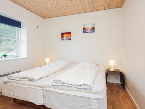 a bed in a white room with two lamps at 4 person holiday home in Nørre Nebel in Nørre Nebel