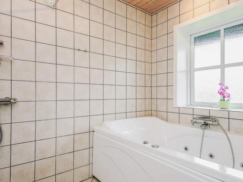 a white tub in a tiled bathroom with a window at 4 person holiday home in Nørre Nebel in Nørre Nebel