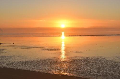 a sunset on the beach with the sun setting at Ferienwohnung Zwergpinscher in Dornum