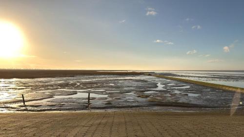 a view of the ocean with the sun in the sky at Ferienwohnung Zwergpinscher in Dornum