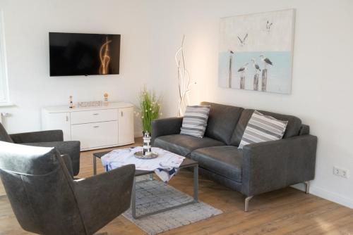 a living room with a couch and chairs and a table at Mole rechts in Norden