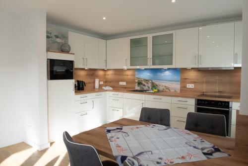 a kitchen with white cabinets and a table and chairs at Mole rechts in Norden