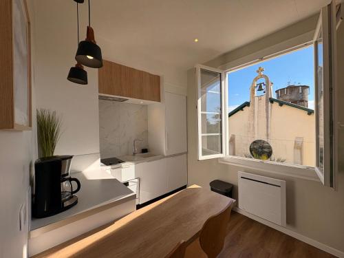 une cuisine avec une table et une fenêtre avec une église dans l'établissement Apartment Erretegia, à Capbreton