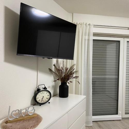 a tv on a wall with a clock on a dresser at Ferienhaus Roomina in Werlte
