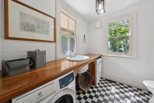 Un baño con lavabo y lavadora. en Brechin Cottage, en Blackheath