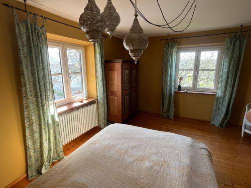 a bedroom with a bed and two windows at Chiemgauer Landliebe in Höslwang