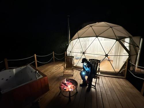 a person sitting in a chair on a deck with a tent at Domos Cusco Glamping & Nature Lodge in Cusco