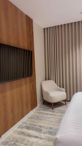 a room with a bed and a chair and a television at شقة دار المنى الفندقية in Al Madinah