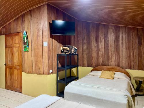 a bedroom with two beds and a tv on the wall at Cabañas La Montaña in Monteverde Costa Rica