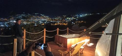 a man standing on top of a balcony at night at Domos Cusco Glamping & Nature Lodge in Cusco