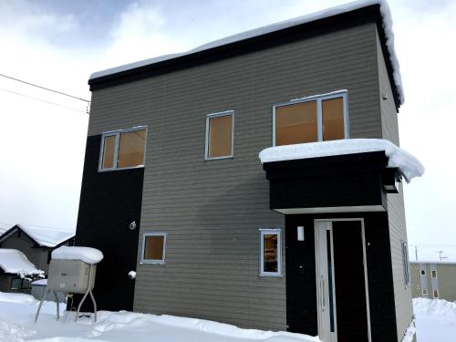 una casa negra con nieve encima en Ume, en Furano
