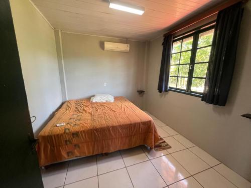 a bedroom with a bed in a room with a window at Recanto Paz in Balneario Barra do Sul