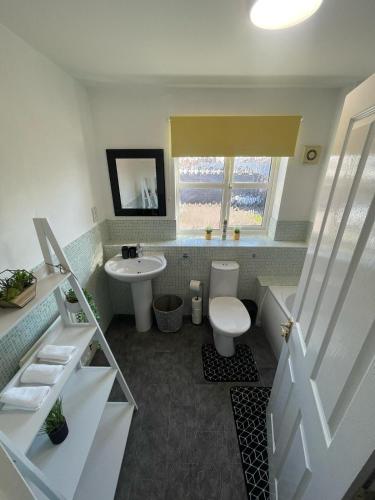 a bathroom with a white toilet and a sink at Miller House in Great location - Sleeps 14! Perfect for contractors in Bedford