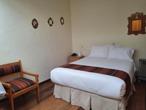 a bedroom with a large bed and a chair at Casona La Recoleta in Cusco