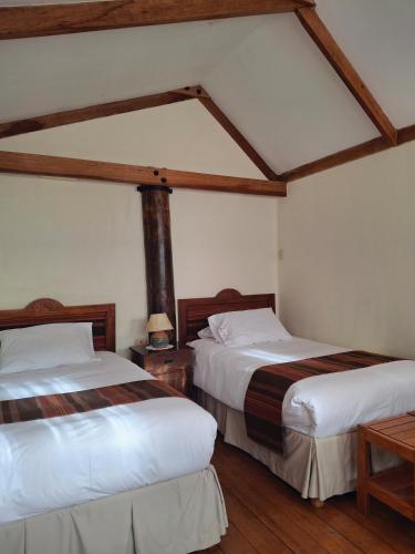 two beds in a room with wooden floors at Casona La Recoleta in Cusco
