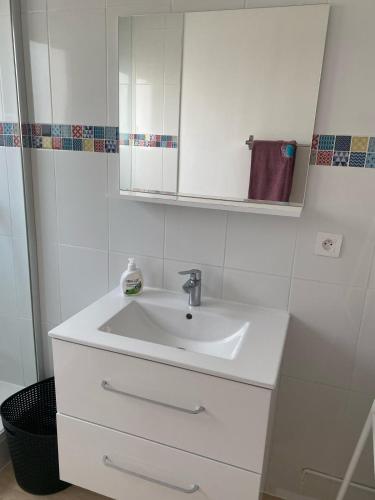 une salle de bain blanche avec un lavabo et un miroir dans l'établissement The Cosy studio Aubervilliers - Metro 12, à Aubervilliers