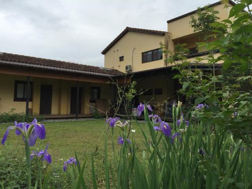 a garden with purple flowers in front of a house at 麵包樹舍 Breadfruit B&B in Guangfu
