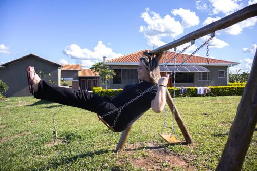 a woman sitting on a swing in a yard at A Casa Cuesta Pousada in Pardinho