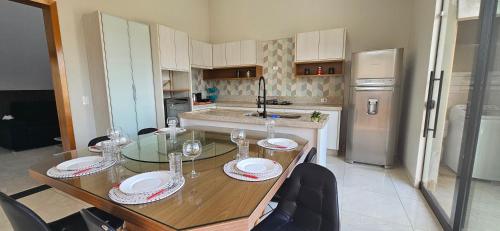 a kitchen with a wooden table with wine glasses on it at Casa Espetacular, 3 suites, luxo! in Maringá