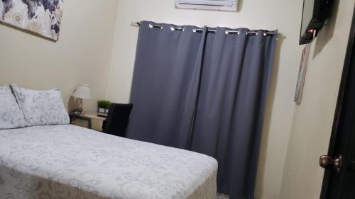 a bedroom with a bed and a blue curtain at Casa Altamira in San Pedro Sula