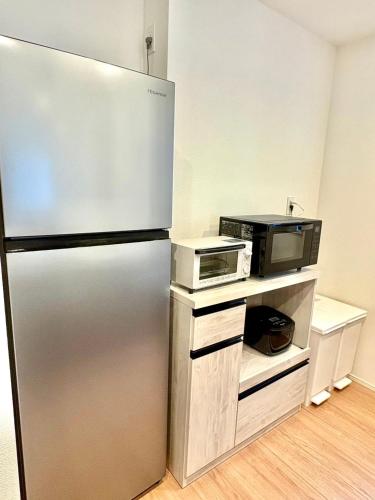 a kitchen with a stainless steel refrigerator and a microwave at Casa Stella 17 by Liaison in Osaka