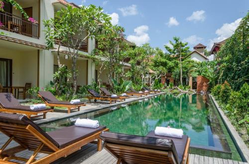 a pool at a resort with chairs and a table at Sapodilla Ubud in Ubud