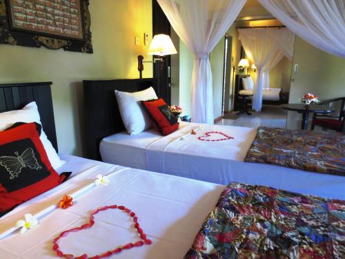 a hotel room with two beds with hearts on them at Taruna Boutique Homestay & Spa in Pemuteran