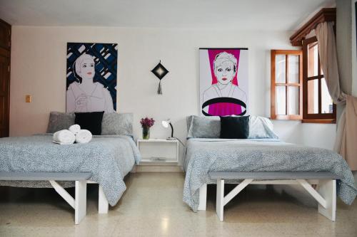 two beds in a room with posters on the wall at Casa Nazimova Indigo Room in San Cristóbal de Las Casas