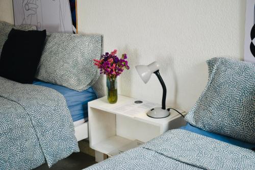 a bedroom with a bed and a table with a lamp and flowers at Casa Nazimova Indigo Room in San Cristóbal de Las Casas