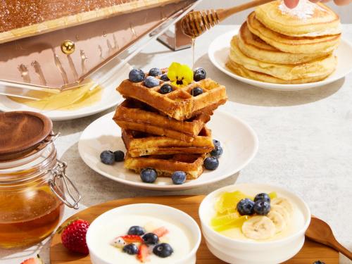 a table topped with plates of waffles and berries at Conrad Bangkok in Bangkok