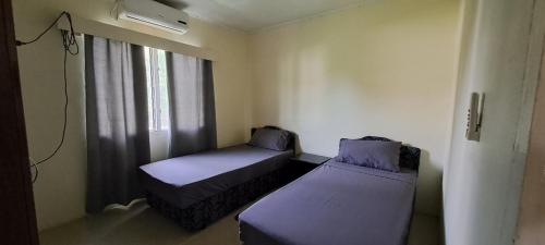 a small room with two beds and a window at ABM Court Apartments in Nadi
