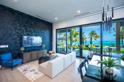 an open living room with a white couch and a tv at Black Urchin Boutique Resort in Belford Estates