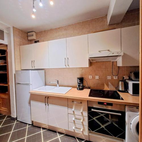 une cuisine avec des armoires blanches et un réfrigérateur blanc dans l'établissement appartement dans la Villa Colibri,, à La Baule