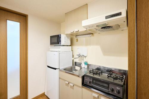a small kitchen with a stove and a refrigerator at C Frase Torikai in Muromimachi