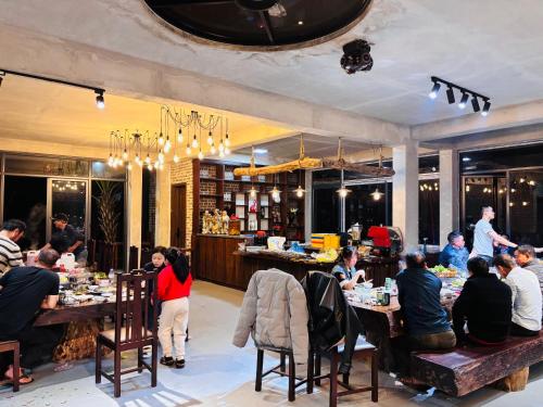 a group of people sitting at tables in a restaurant at BIRD HOUSE villa in Hữu Biêt