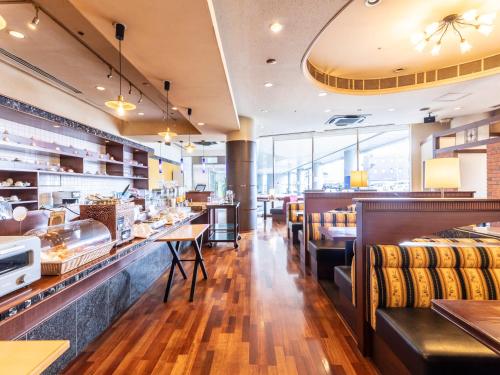 a restaurant with a counter and tables and chairs at Century Plaza Hotel in Tokushima