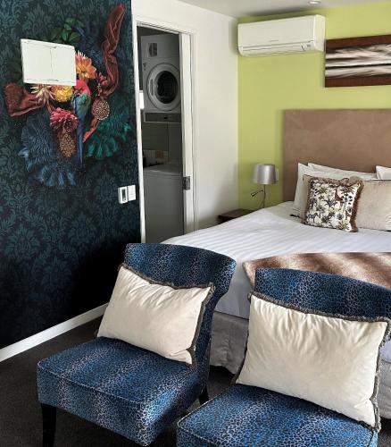 a bedroom with a bed and two blue chairs at Delorenzo Studio Apartments in Nelson