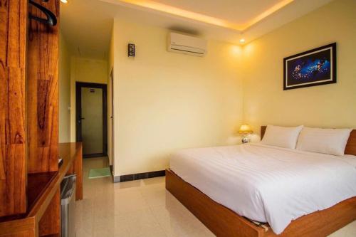 a bedroom with a white bed and a television at Gold Stone Hoi An Homestay in Hoi An