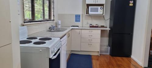 a kitchen with a stove and a sink and a refrigerator at Methven Motel & Apartments in Methven