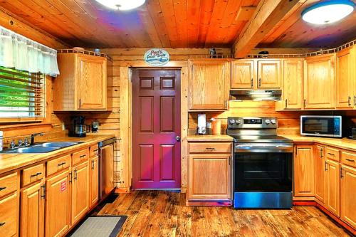 a kitchen with wooden cabinets and a purple door at Wonderland Cabin in Sevierville