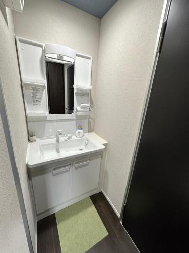 een witte badkamer met een wastafel en een spiegel bij 福ホテル501 in Tokyo