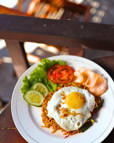 a plate of food with a fried egg and vegetables at Umahita Lodge Penida in Toyapakeh