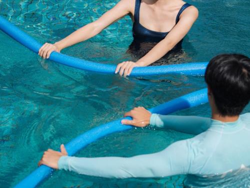 two people in the water holding onto blue tubes at The Terrace Club Wellness Thalasso At Busena in Nago