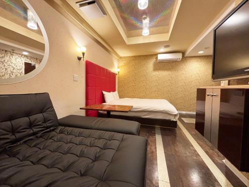 a living room with a couch and a bed at 1st STEP HOTEL ファーストステップホテル in Tokyo