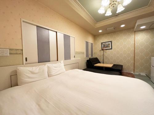 a bedroom with a large white bed and a chair at 1st STEP HOTEL ファーストステップホテル in Tokyo