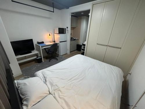 a bedroom with a white bed and a desk at SABBATH uzumasa 102 in Kyoto